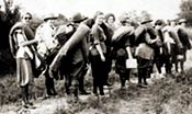 Black-and-white photo of Girl Scouts hiking with bedrolls in the 1920s.